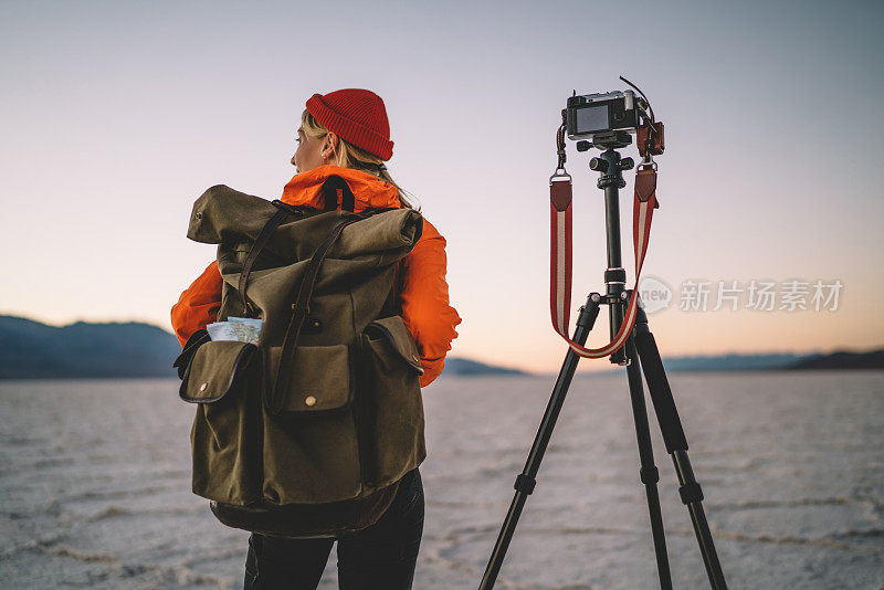女摄影师背着背包准备拍摄风景环境视频的背影，女摄影师用现代设备和三脚架拍摄Badwater basin